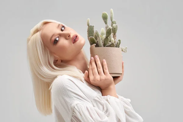 Menina loira bonita com maquiagem segurando pote com cacto — Fotografia de Stock