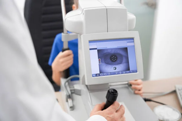 Oculista masculino inteligente usando a máquina para verificar a visão dos olhos — Fotografia de Stock