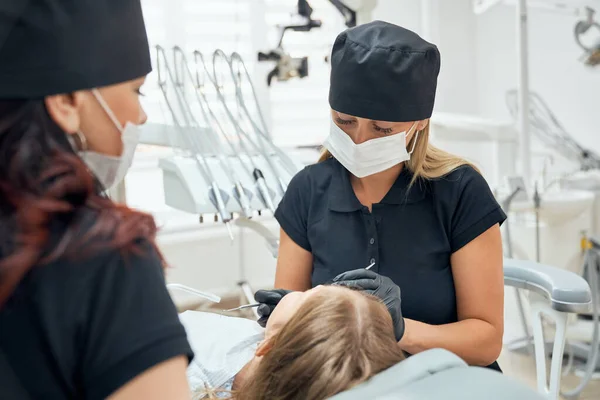 Vista desde un lado de dentistas femeninos en proceso de curación de dientes — Foto de Stock