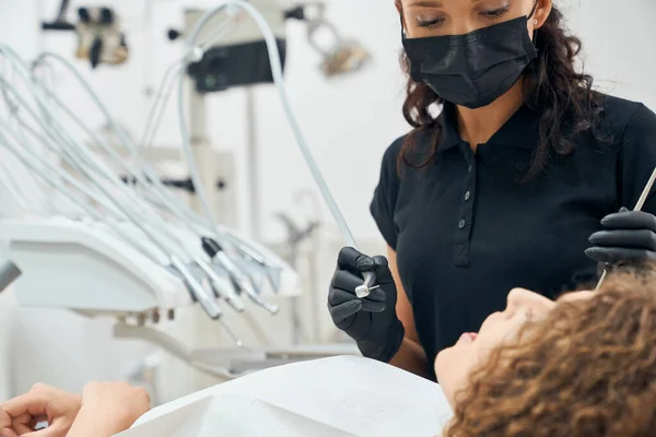 Dentista experto en uniforme y mascarilla para curar los dientes del paciente — Foto de Stock