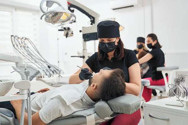 Arzt hält Sonde und Spiegel und untersucht Zähne — Stockfoto