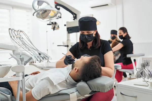 Médico mantendo sonda e espelho e examinando dentes — Fotografia de Stock