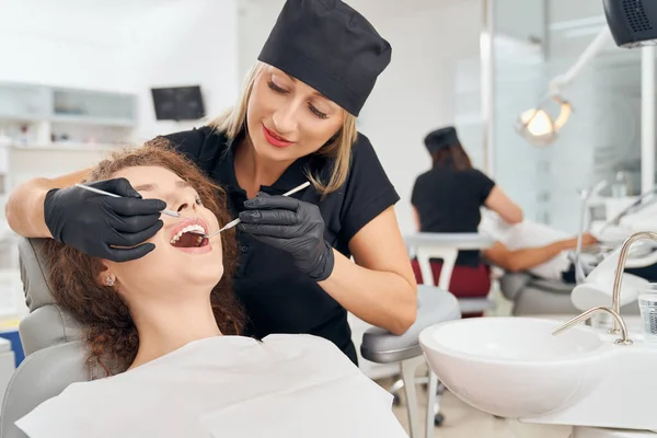 Dişleri tedavi eden profesyonel kadın dişçi. — Stok fotoğraf