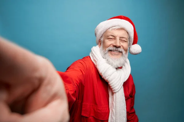 Senior bearded man in Santa costume and scarf taking selfie — Stock Fotó