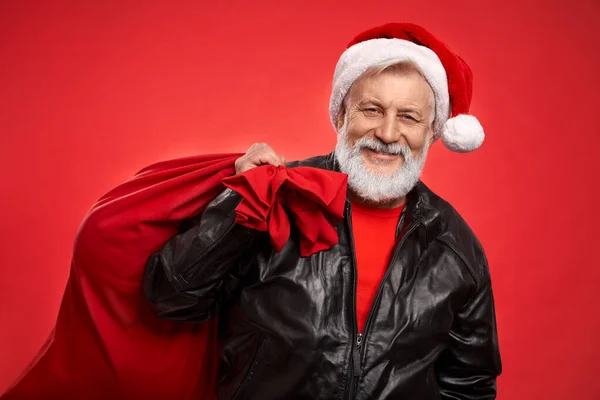 Dojrzały mężczyzna w kapeluszu Santa i skórzana kurtka z czerwonym workiem — Zdjęcie stockowe