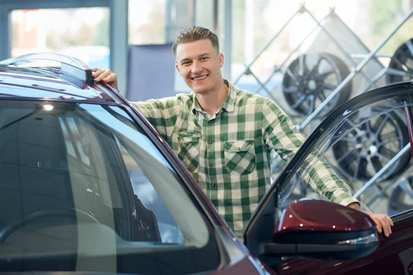 Leende man lutar sig mot bilen i återförsäljaravtal. — Stockfoto