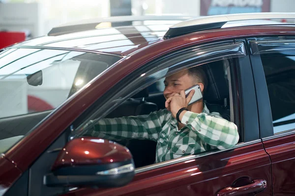 Pria Bahagia menggunakan telepon dalam mobil di dealer. — Stok Foto
