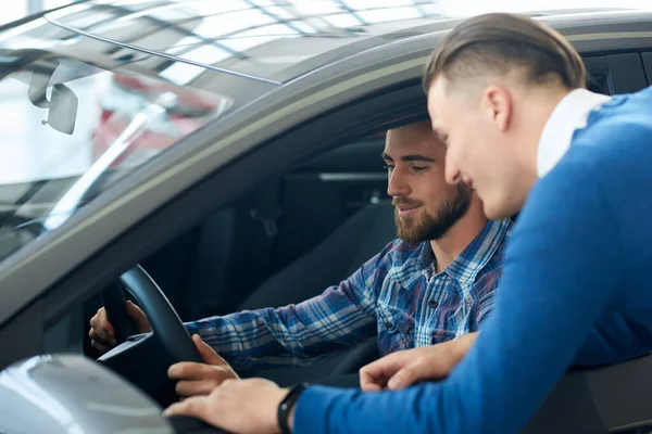 Vendeur de voiture montrant la voiture client dans le concessionnaire . — Photo