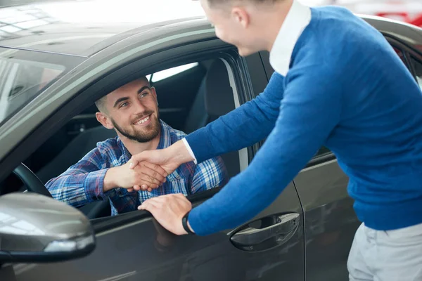 Vendedor de coches y el cliente apretón de manos en concesionario de coches . — Foto de Stock