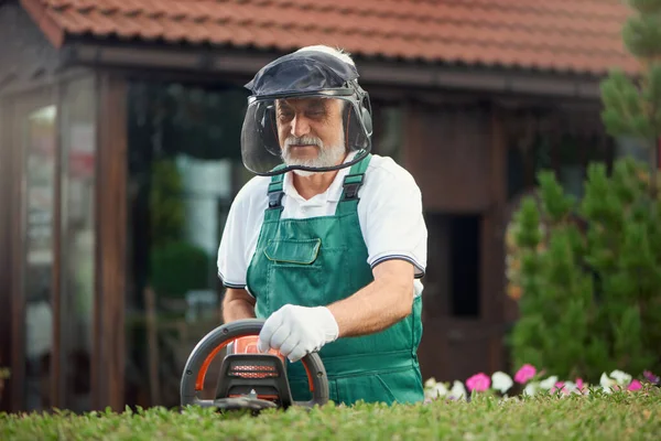 Jardinero usando protección usando máquina de recorte . — Foto de Stock