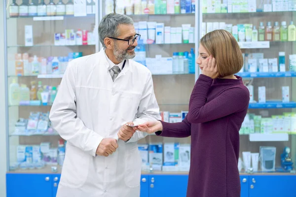 Mujer gicing farmacéutico con pastillas para el dolor de cabeza . — Foto de Stock