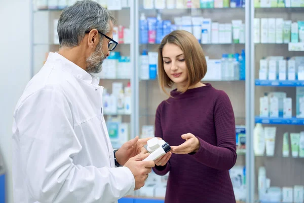 Female customer and pharmacist choosing medicine.