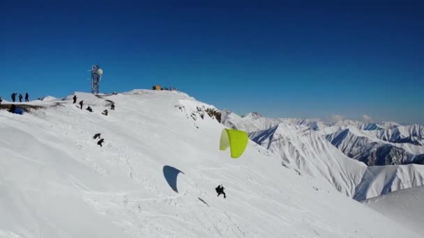 Gleitschirmflieger fliegen über verschneiten Bergen. — Stockvideo