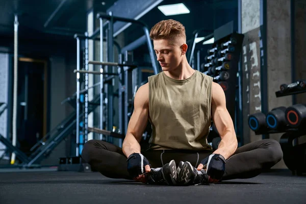 Mannen som stretchar fjäril på golvet i gymmet. — Stockfoto