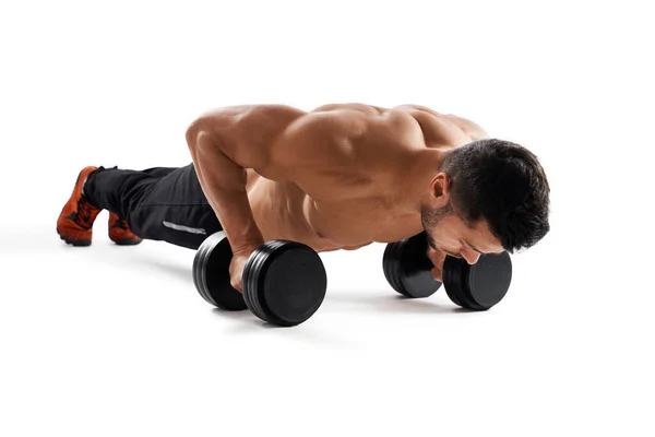 Musculaire man doet push-ups met behulp van halters. — Stockfoto