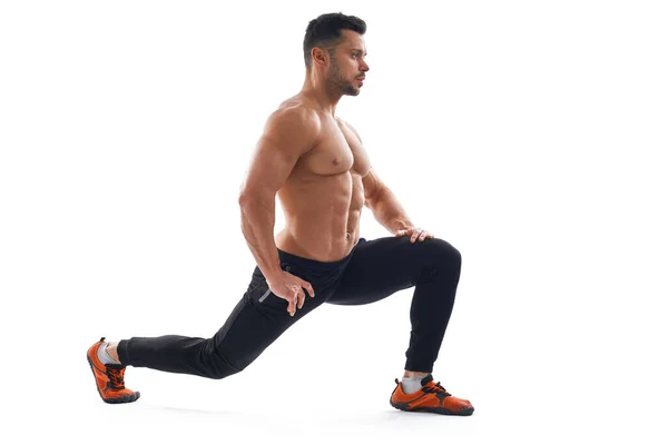 Fisicoculturista sin camisa estiramiento, aislado en blanco . — Foto de Stock