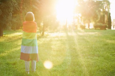 Omuzlarında gökkuşağı bayrağı taşıyan tanınmayan bir kadın..