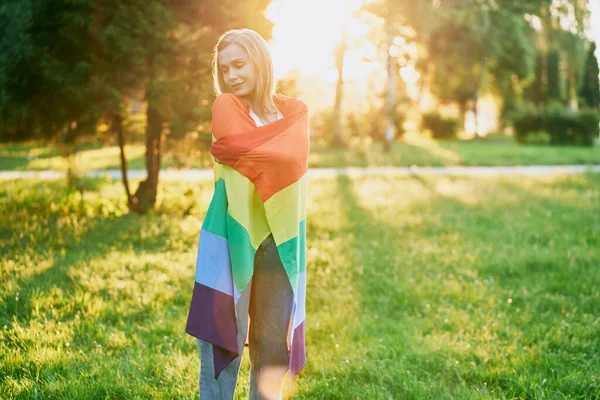 Vrolijke jonge vrouw met regenboogvlag op de schouders. — Stockfoto