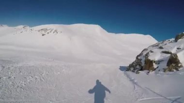 Elinde kamerayla yamaçta gezen snowboardcu..