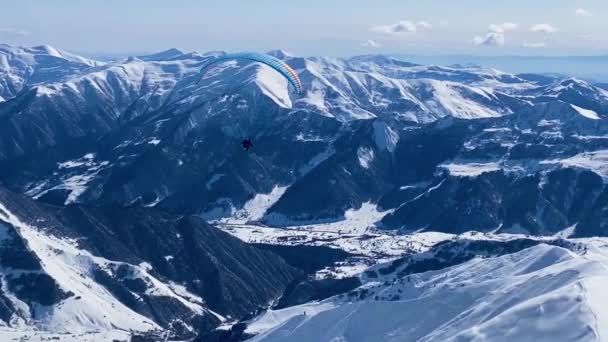 Αλεξίπτωτο πετούν πάνω από το χειμώνα βουνά τοπίο. — Αρχείο Βίντεο