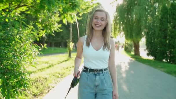 Ung kvinna går med fransk bulldogg i parken. — Stockvideo