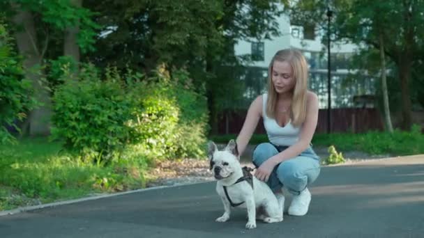 Ung kvinna petting fransk bulldog i parken. — Stockvideo