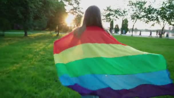 Mujer corriendo con bandera de arco iris, mostrando tolerancia. — Vídeos de Stock