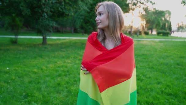 Mujer tolerante sosteniendo la bandera del arco iris alrededor del cuerpo . — Vídeo de stock