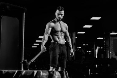 Lastiklerin üzerinde balyoz tutan kaslı vücut geliştirici.