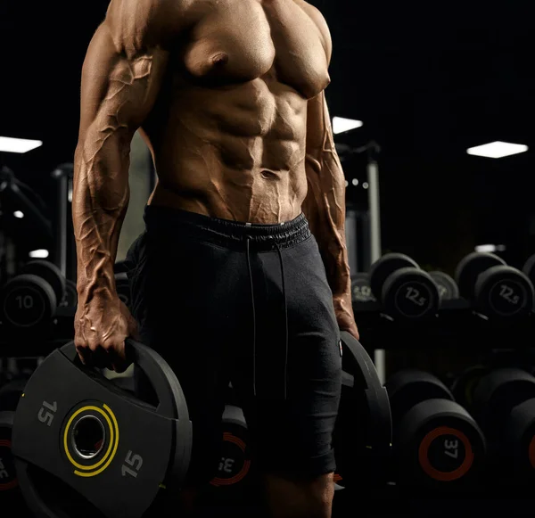 Musculación masculina tensa que sostiene pesas . — Foto de Stock