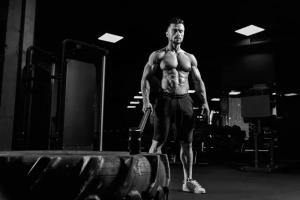 Muscular hombre sosteniendo martillo en el gimnasio. —  Fotos de Stock