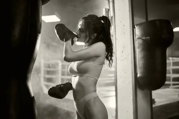 Samice boxer zapínání rukavice s ústy, monochromatický. — Stock fotografie