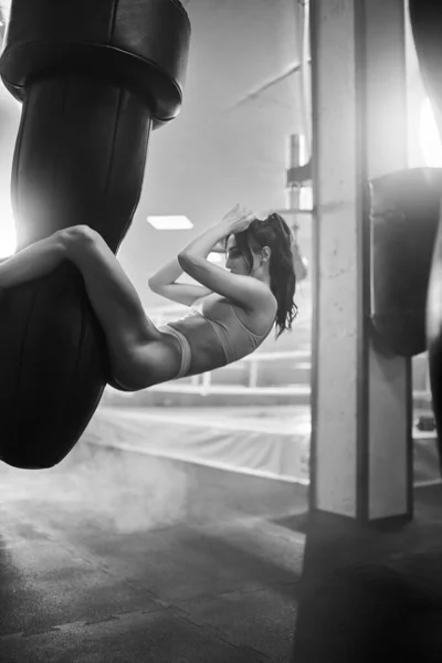 Vrouw training buikspieren op bokszak. — Stockfoto