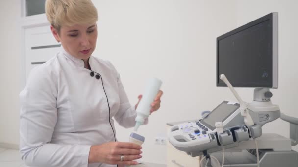 Az orvos folyadékot tesz az ultrahangos készülékre.. — Stock videók