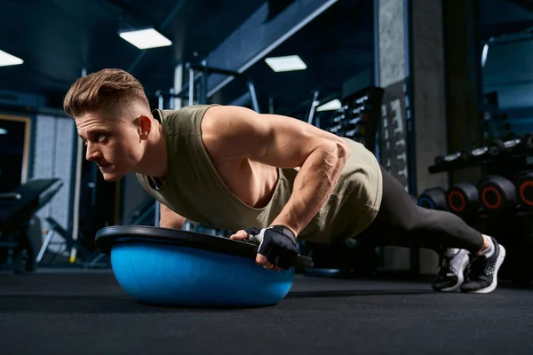 Muskulös man gör armhävningar med hjälp av balansboll. — Stockfoto