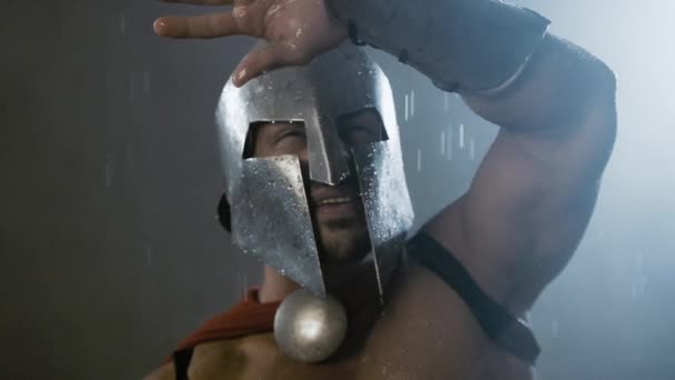 Spartan gömmer sig från regn med arm. — Stockvideo