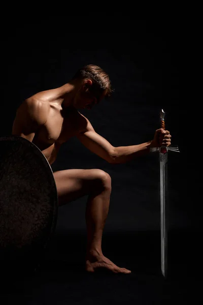 Warrior with sword standing on knee. — Stock Photo, Image