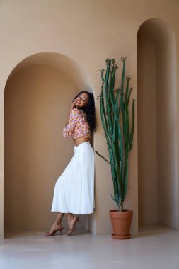 Gülümseyen melez kadın model içeride poz veriyor..