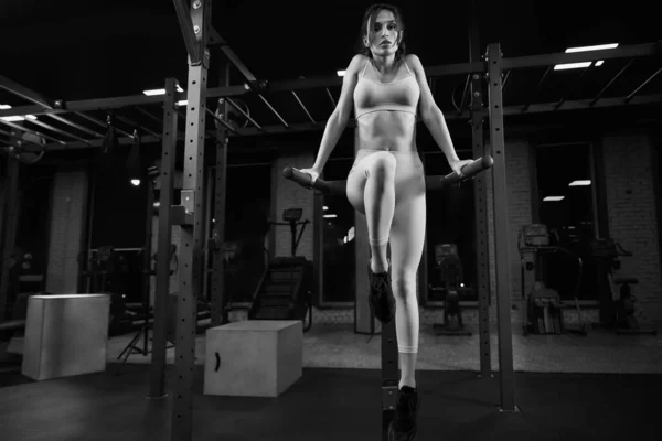 Femme posant sur des barres parallèles dans la salle de gym. — Photo