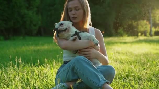 Feliz joven acariciando bulldog francés al aire libre . — Vídeo de stock