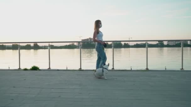 Mujer con mascarilla blanca paseando con perro. — Vídeos de Stock