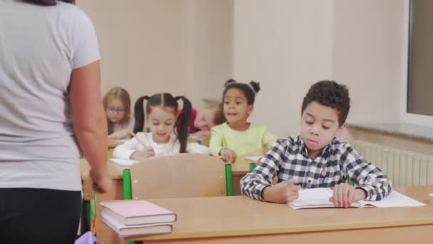 Profesor revisando copybook de alumno en el aula . — Vídeo de stock