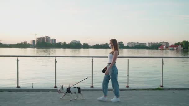 Femme portant un masque blanc marchant avec chien. — Video