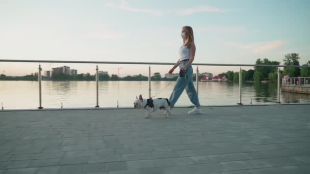 Mujer joven con máscara facial paseando con perro. — Vídeos de Stock