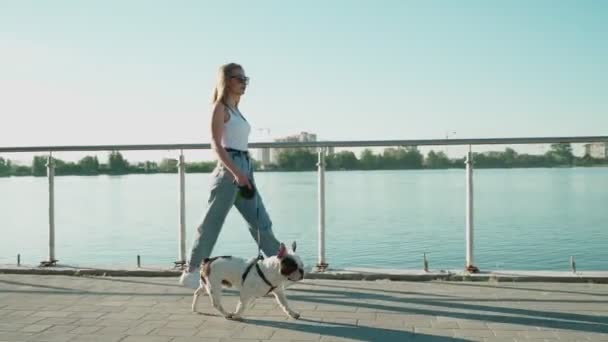 Giovane donna a piedi con bulldog francese vicino al lago. — Video Stock