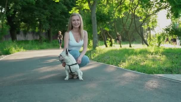 微笑的女人在公园里爱抚法国斗牛犬. — 图库视频影像