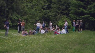 Ormanda hasırların üzerinde oturan gençler.