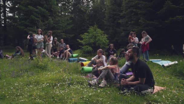 Підлітки сидять на килимках у лісі . — стокове відео