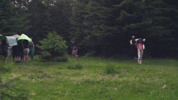 Dospívající pomocí rohoží jako deštníky v lese. — Stock video