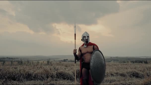 Spartanin bez koszuli podnosi ręce na suchym polu. — Wideo stockowe